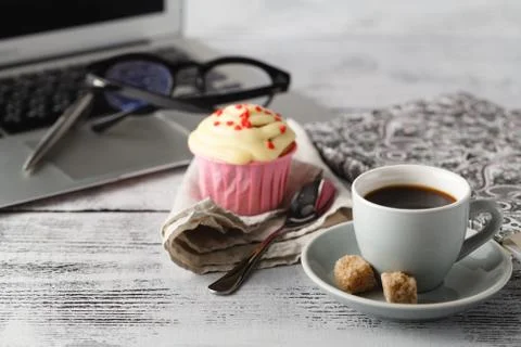 Coffee cup and muffin on table with computer Stock Photos