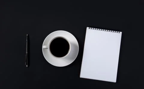 Coffee cup and white notepad with pen on black background. top view Stock Photos
