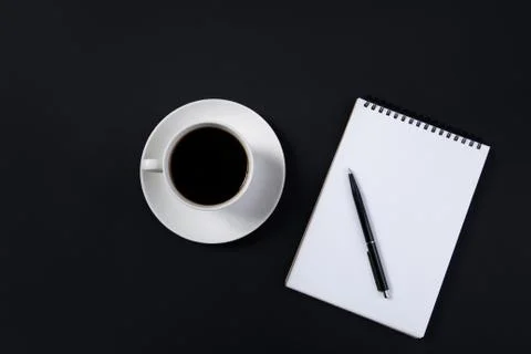 Coffee cup and white notepad with pen on black background. top view Foto stock