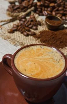 Coffee cup on the background of coffee beans on the table. Stock Photos