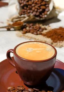 Coffee cup on the background of coffee beans on the table. Stock Photos