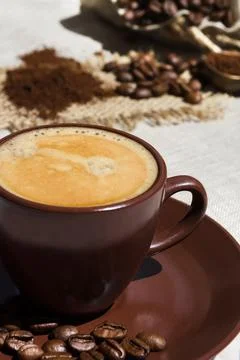 Coffee cup on the background of coffee beans on the table. Stock Photos
