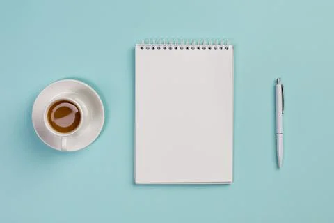 Coffee cup blank spiral notepad pen blue office desk Stock Photos