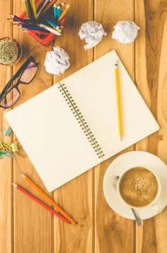 Coffee cup, chart, pen, notebook and accessory for work on wooden table. Stock Photos