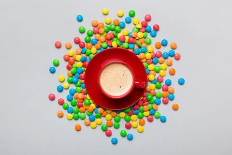 Coffee cup with chocolates and colored candy. Top view on table background wi Stock Photos