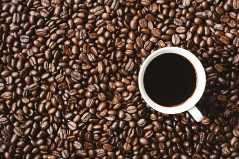 Coffee in a cup on coffee beans background. Stock Photos