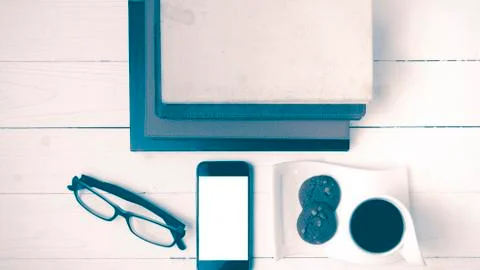 Coffee cup with cookie,phone,stack of book and eyeglasses vintag Fotos de archivo