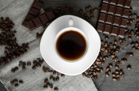 Coffee cup with cookies and chocolate with scattered coffee beans on linen and Stock Photos