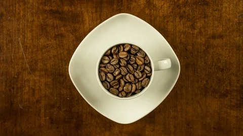 Coffee cup filled with beans stop motion animation turning clockwise top view Stock Footage 92054924