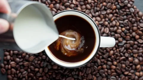 Coffee cup filled with black coffee. Cup is surrounded by roasted coffee beans. Video stock 278034142