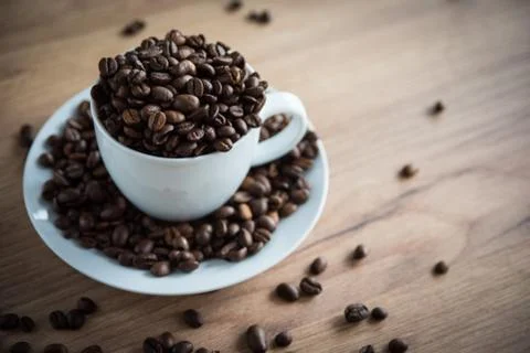 Coffee cup filled by coffee beans on wooden background Stock Photos