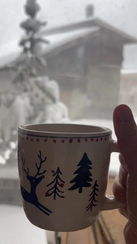 Coffee cup in front of a snowing window in winter by Christmas Stock Footage 336961757