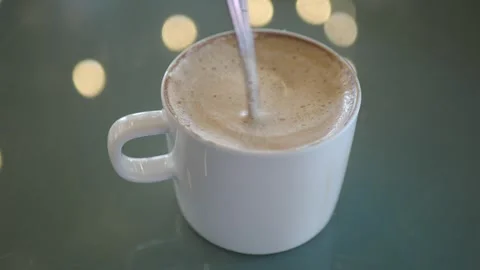 Coffee cup with frothy drink and spoon stirring Stock Footage 325442043