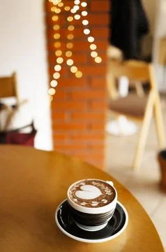 Coffee cup with heart pattern on wooden table in coffee shop Stock Photos