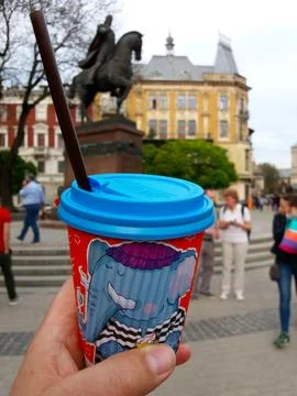 Coffee Cup Held in Hand With Monument Backdrop in a Lively Urban Square Dur.. Stock Photos