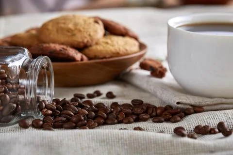 Coffee cup, jar with coffee beans, cookies over homespun tablecloth, selective Stock Photos