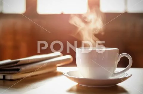 Coffee cup with newspaper on the table, coffee shop background, warm tone Stock Photos