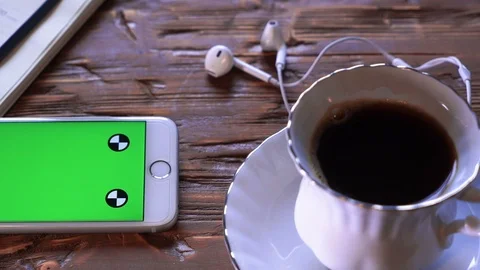 Coffee cup next to the mobile device both on a wooden table. Studio shot. Stock Footage 85576666