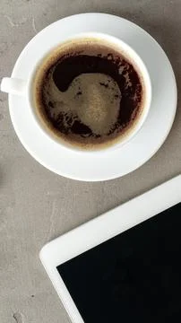 Coffee in cup next to tablet on table in a cozy setting during daytime Stock Photos