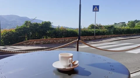 Coffee cup on an outdoor table in La Spezia, Italy, overlooking a sunny street Stock Footage 345523396