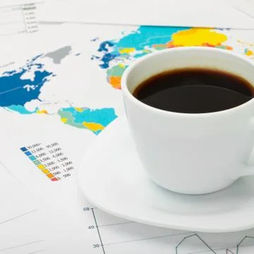 Coffee cup over world map and some financial documents Stock Photos