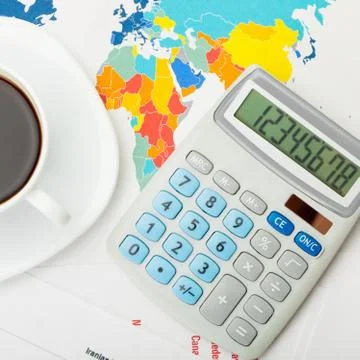 Coffee cup over world map and financial documents - view from top Stock Photos