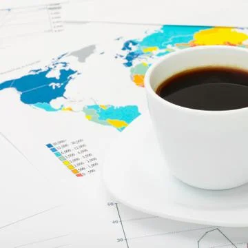 Coffee cup over world map and some financial documents Фото