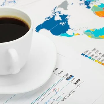 Coffee cup over world map and some market charts Фото