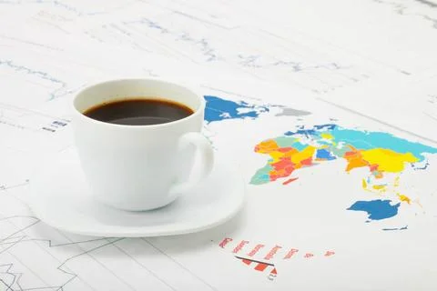  Coffee cup over world map and financial documents - studio shot Coffee cu... Фото