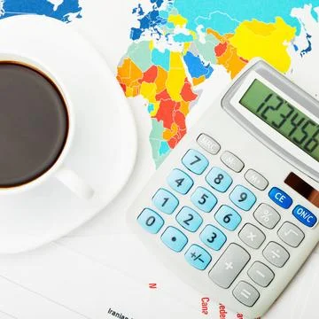 Coffee cup over world map and financial documents - view from top Coffee c... Stock Photos