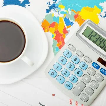 Coffee cup over world map and financial documents - view from top Coffee c... 写真素材