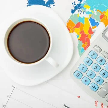 Coffee cup over world map and financial documents - view from top Coffee c... Stockfoto's