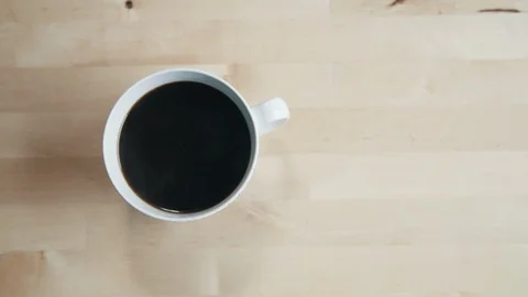 Coffee cup overhead on plain wood kitchen counter Video stock 97734751