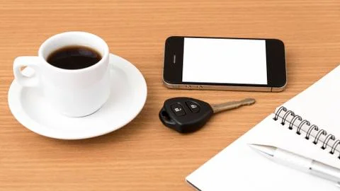 Coffee cup with phone car key and notepad Stock Photos