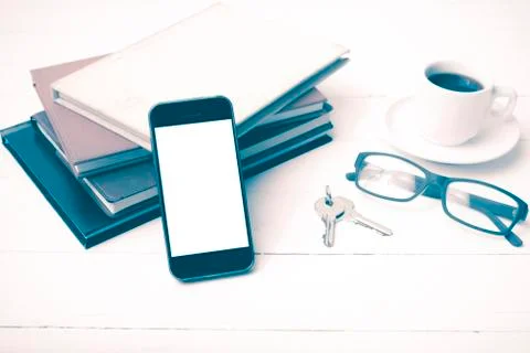 Coffee cup with phone,key,eyeglasses and stack of book vintage style Stock Photos