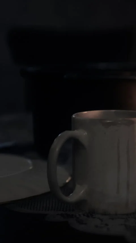 Coffee cup placed on a table with warm light from a candle in the background Stock Footage 342660808