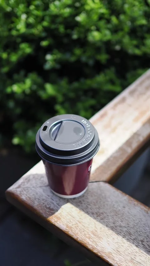 Coffee cup placed on a wooden table in a relaxed outdoor setting Stock Footage 346665040