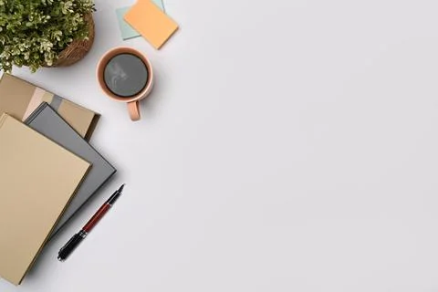 Coffee cup, potted plant and notebooks on white table. Copy space. Stock Photos