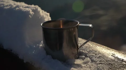 Coffee cup resting on snowy ledge at sunrise in winter landscape Stock Footage 307832745