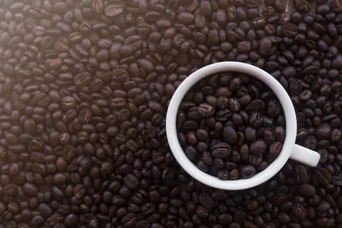 Coffee cup with roasted beans on coffee beans background. Top view with copy  Stock Photos