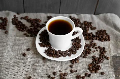 Coffee cup with roasted coffee beans on linen background. Mug of black coffe Stock Photos