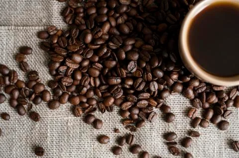 Coffee cup with roasted coffee beans on linen background. Mug of black coffe Stock Photos
