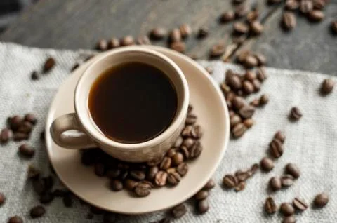 Coffee cup with roasted coffee beans on wooden table background. Mug of black Stock Photos