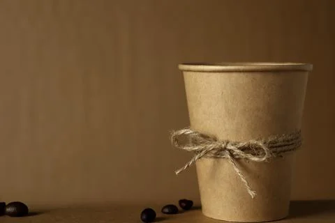 Coffee cup sits on a table with coffee beans scattered around in soft lighting Stock Photos