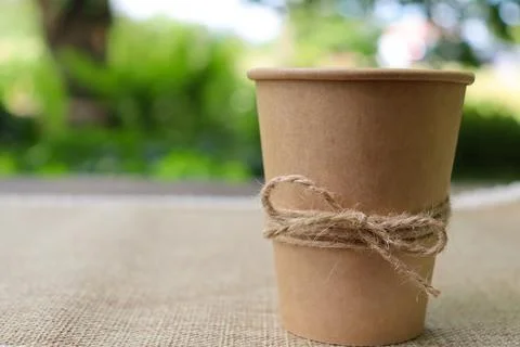 Coffee cup sits on a table in a garden during a sunny day with greenery in the 스톡 사진