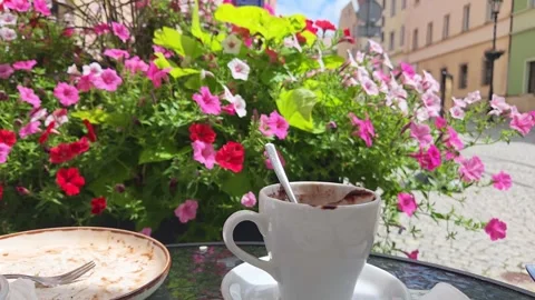 Coffee cup with spoon beside empty dessert plate on outdoor cafe table, colorful Stock Footage 346848117