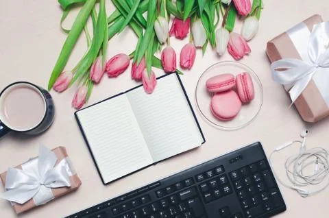 Coffee cup, spring tulip flowers and pink macarons and keyboard and earphones Stock Photos