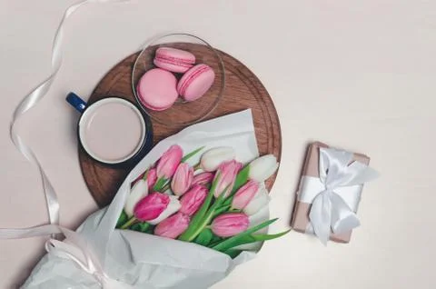 Coffee cup, spring tulip flowers and pink macarons on wooden table top view.  Stock Photos