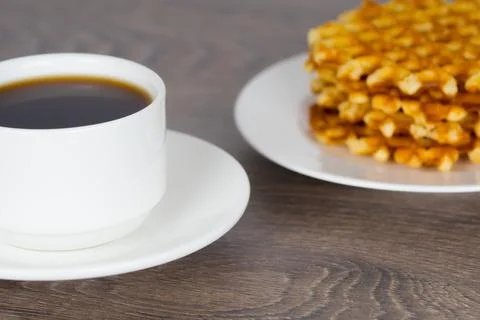 Coffee cup with stack of belgian round waffles on wooden table Stock-Fotos
