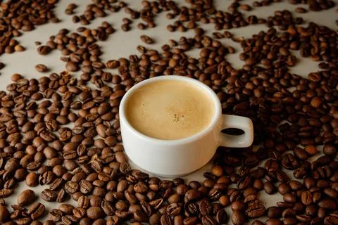 Coffee cup surrounded by aromatic roasted beans in a vibrant café setting Stock Photos